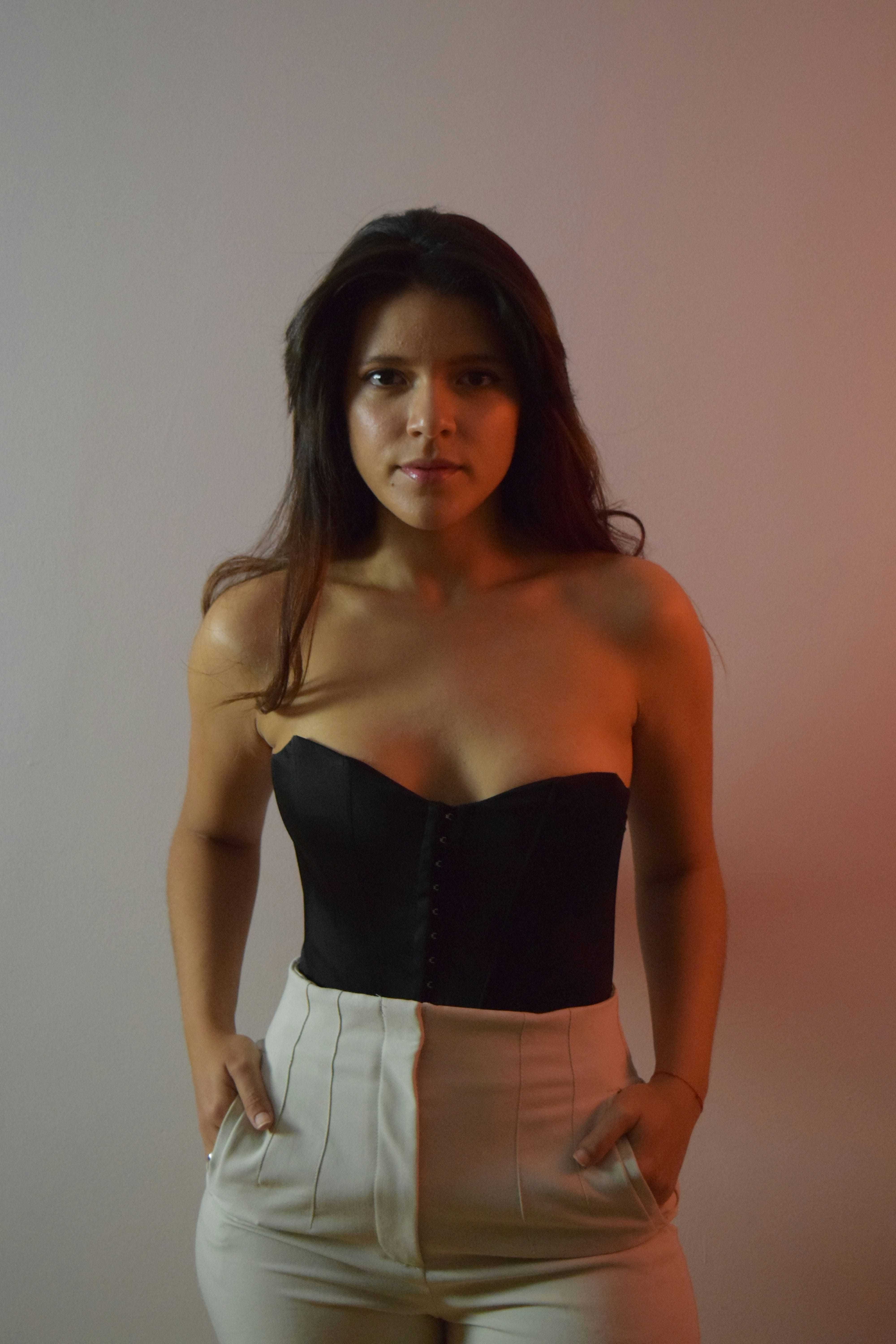 Woman in a black strapless corset and high-waisted white pants posing confidently in 2025