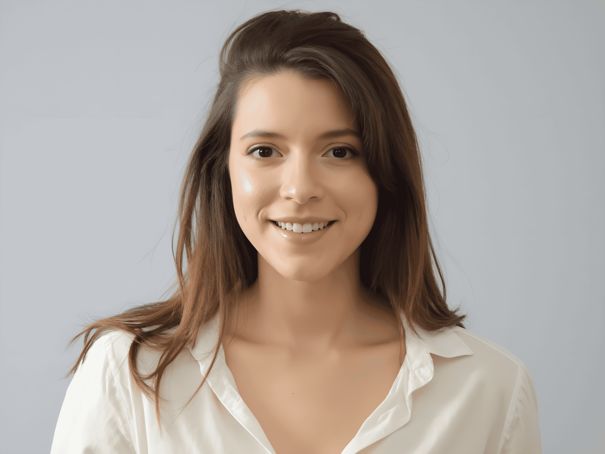 Smiling young woman with long brown hair wearing a white shirt, against a neutral background.